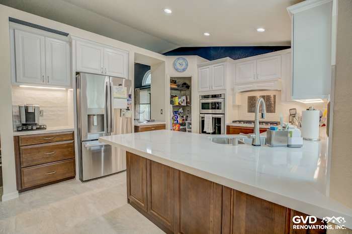 Bright modern kitchen featuring white cabinets, quartz countertop, stainless steel appliances, and a spacious island
