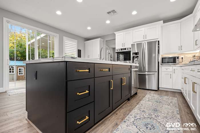 Modern kitchen remodel in Roseville featuring a dark island, white cabinets, and Cambria countertops