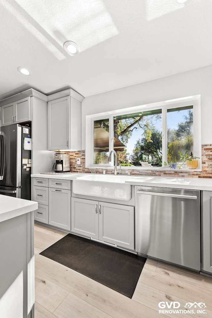 Light gray cabinetry and stainless steel appliances in a modern Greenwood kitchen remodel, featuring a large window