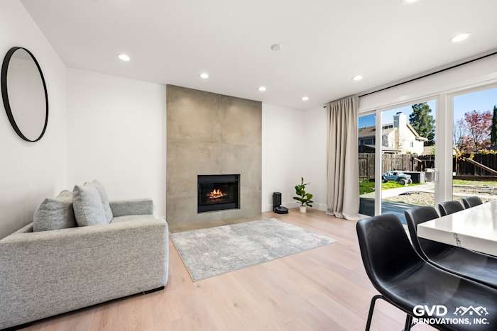 Modern living room featuring a sleek concrete fireplace, light wood flooring, and stylish gray furniture