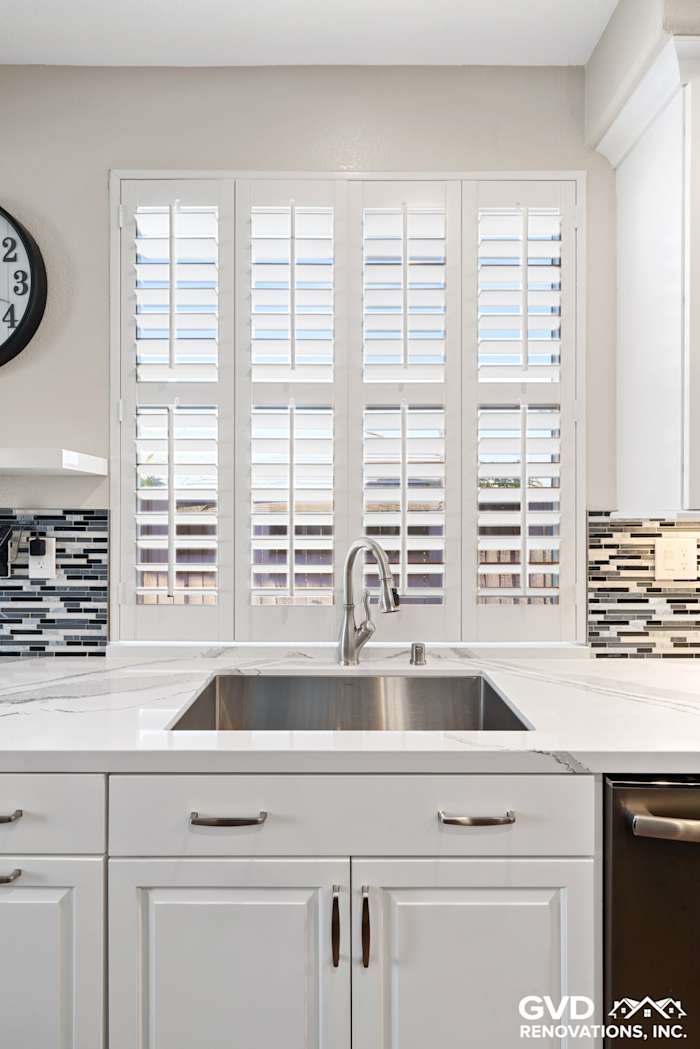 Modern kitchen sink with white cabinetry, marble countertop, and stylish window shutters in El Dorado Hills