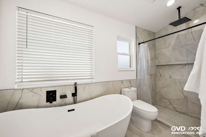 Modern bathroom featuring a luxurious freestanding tub, dual vanities, and elegant marble walls in Antelope, CA