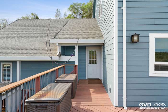 Newly installed James Hardie siding in blue on a house exterior, featuring a wooden deck and door entrance