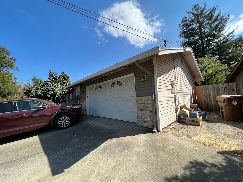 Exterior view of a Sacramento home featuring a garage, stone accent, and clear blue skies
