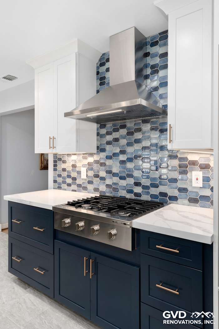 Modern kitchen featuring navy blue cabinetry, a hexagonal blue backsplash, and a stainless steel range hood