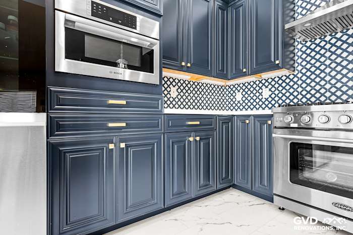 Navy blue cabinetry with gold hardware, stainless steel appliances, and patterned backsplash in remodeled Sacramento kitchen