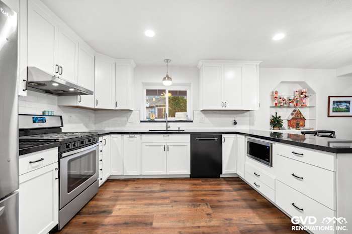 Bright white shaker cabinets, dark countertops, stainless steel appliances, and stylish lighting in a remodeled Loomis