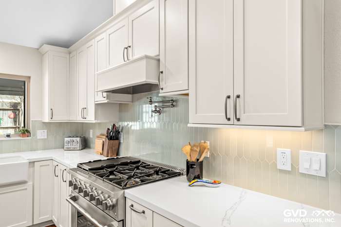 Modern kitchen in Carmichael featuring custom white cabinetry, stainless steel range, and light green hexagonal backsplash
