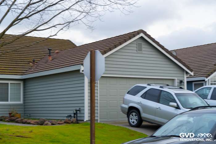 New Prodigy Solid Core Insulated Siding in light gray with painted eaves, modern garage door, and landscaping