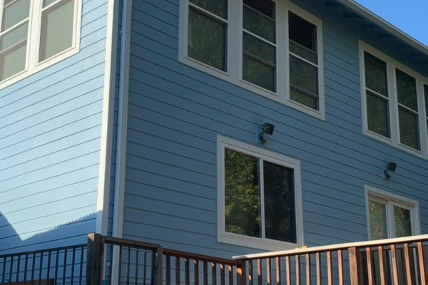 Light blue James Hardie fiber cement siding and new vinyl windows on a renovated Oakland home exterior