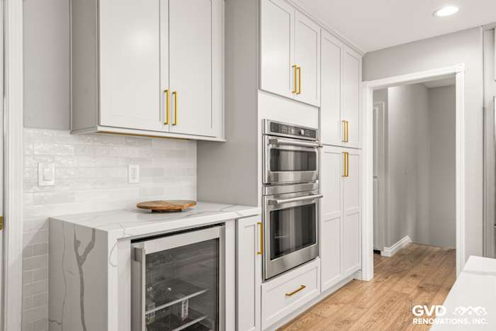 Modern kitchen with white custom cabinets, quartz countertop, built-in double ovens, and wine cooler in El Dorado Hills