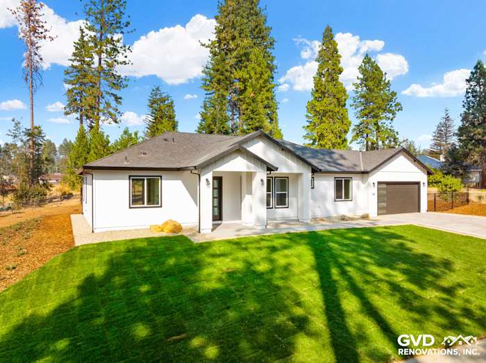 Modern single-story home exterior with white stucco, black roof, and landscaped lawn in Paradise, CA