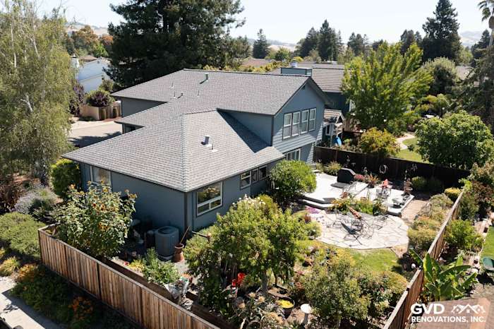 Back view of a home with Boothbay Blue James Hardie siding and new Milgard windows, surrounded by lush landscaping