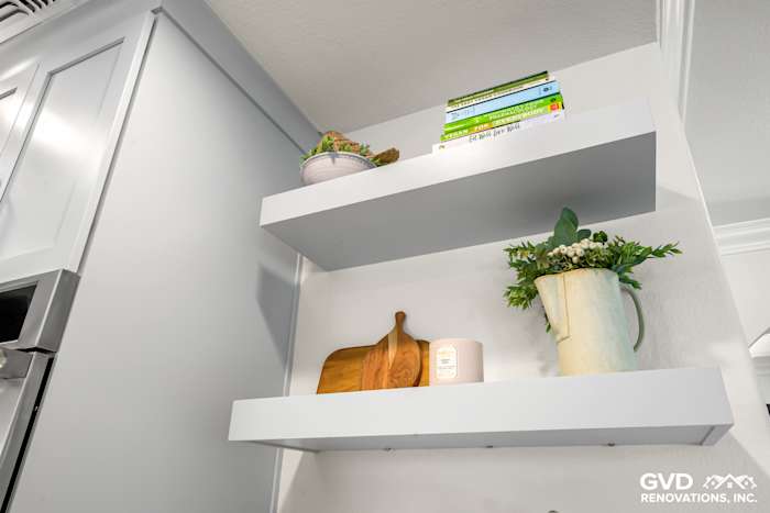 Open kitchen shelving with decorative plants, cookbooks, and wooden utensils in a modern Rocklin kitchen remodel