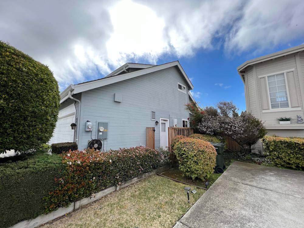 Side view of a Sacramento home with landscaped yard and cloudy sky backdrop