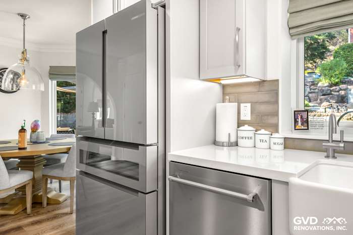 Modern kitchen with stainless steel refrigerator, white quartz countertop, and stylish cabinet details