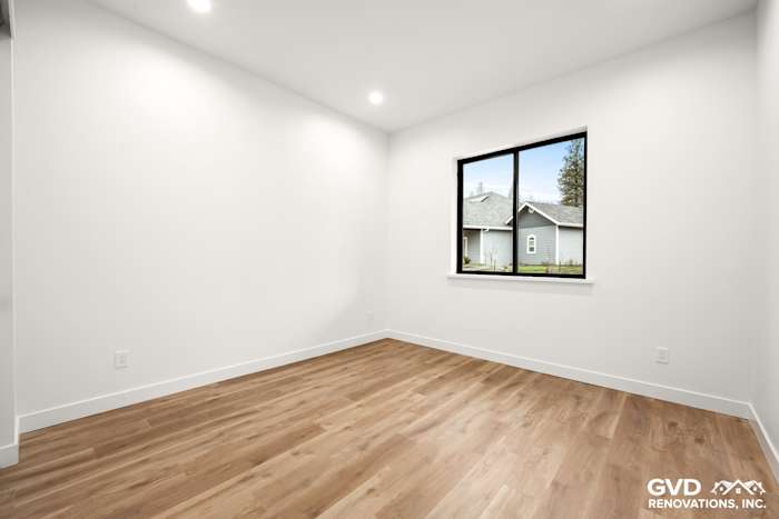 Bright, empty bedroom with large window, white walls, and light wood flooring in new construction home