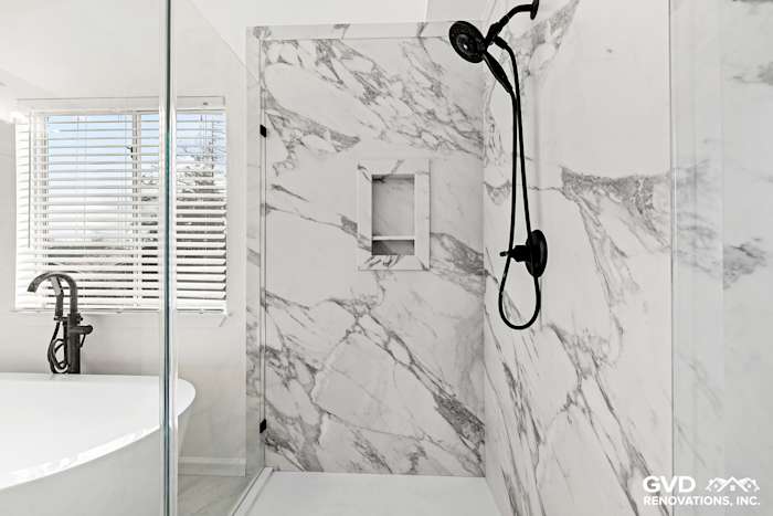 Modern bathroom remodel featuring a walk-in shower with marble walls and black fixtures in Sacramento