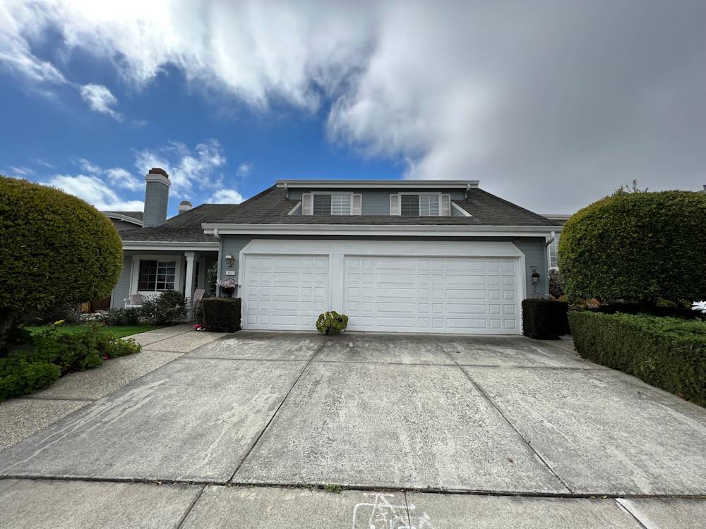 Spacious Sacramento driveway with concrete surface, manicured hedges, and cloudy sky backdrop