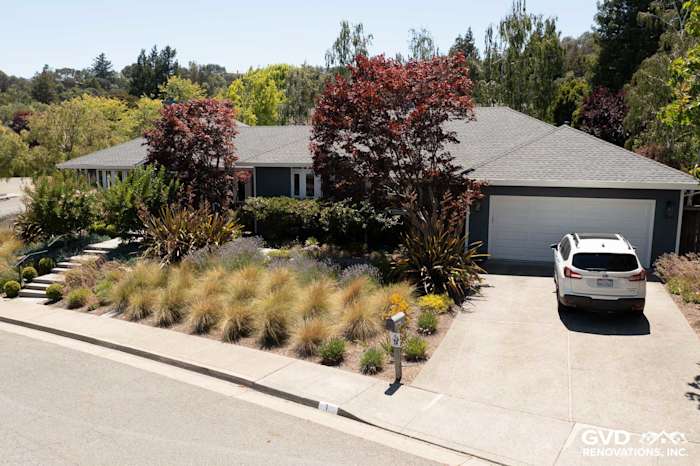 Modern home exterior with James Hardie Evening Blue lap siding and Arctic White trim, surrounded by lush landscaping