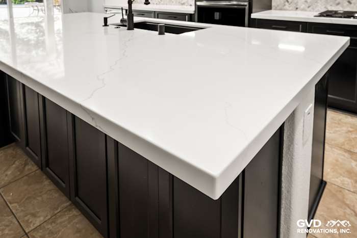 Quartz countertop with custom mitered edge over dark Waypoint cabinets in a remodeled kitchen