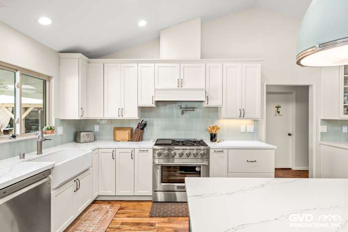 Bright kitchen remodel in Carmichael featuring custom white cabinets, a sleek backsplash, and stainless steel appliances