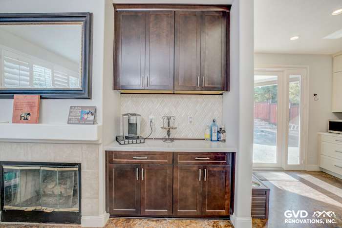 Modern kitchen remodel in Roseville featuring dark wood cabinets, herringbone backsplash, and a cozy fireplace