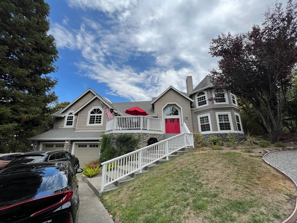 Two-story home in Sacramento with a welcoming porch, vibrant red door, and manicured landscaping