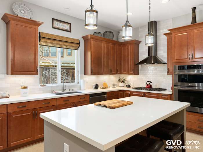 Modern kitchen with brown wood cabinets, quartz countertop island, and stainless steel appliances in Elk Grove
