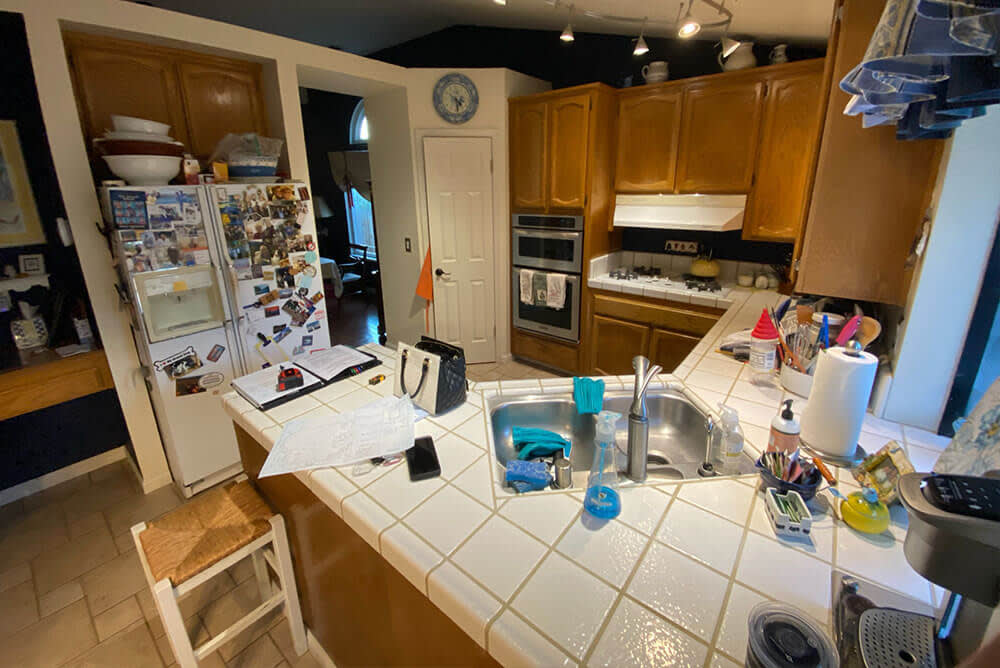 Dark wooden cabinets, white tile countertops, and cluttered kitchen space in Sacramento