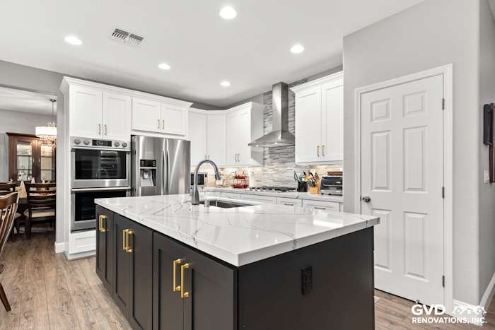 Modern kitchen featuring Cambria countertops, custom white cabinets, and a dark island with gold hardware in Roseville