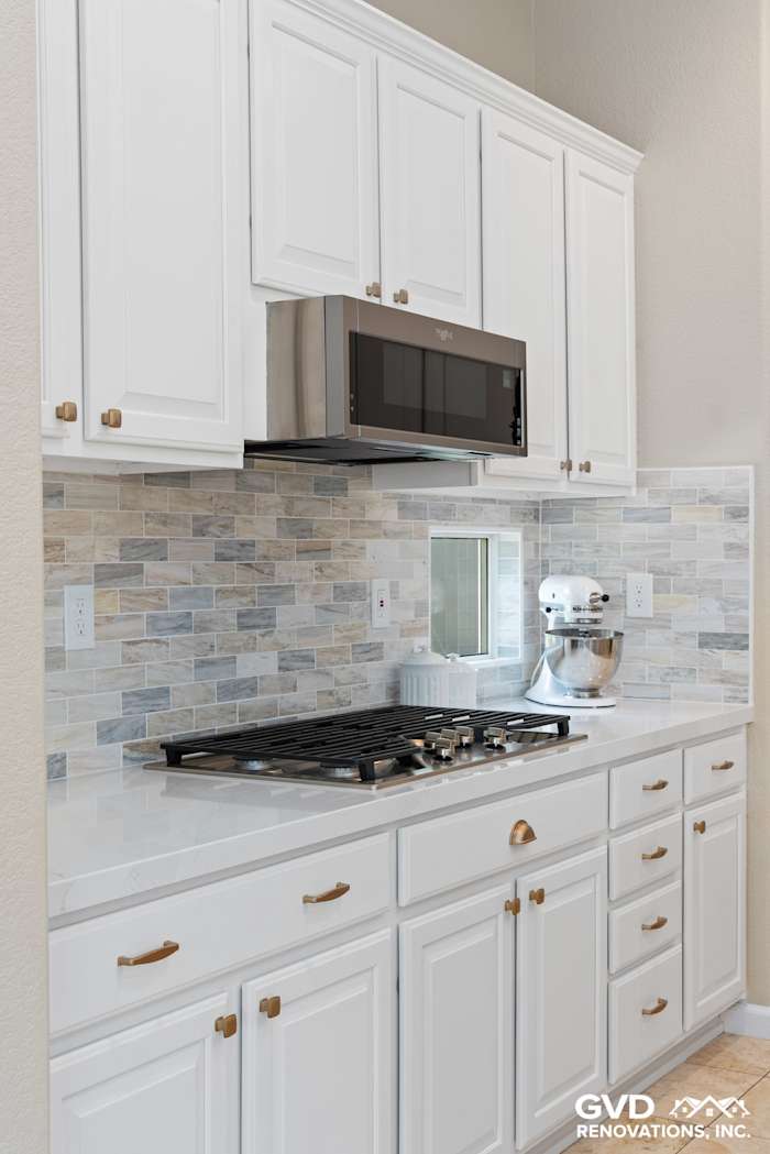 Modern kitchen featuring white cabinets, quartz countertop, and a striking blue and gray backsplash
