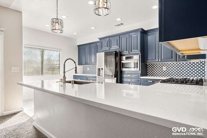 Modern kitchen with navy blue cabinets, white quartz countertops, and stylish pendant lighting in Sacramento remodel