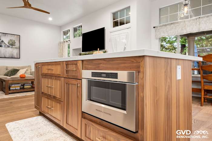 Modern kitchen island with walnut cabinets, built-in microwave, and quartz countertop in Folsom, CA remodel