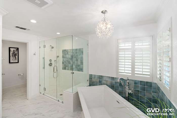 Bright bathroom with glass shower, freestanding tub, and blue tile accents for a serene retreat