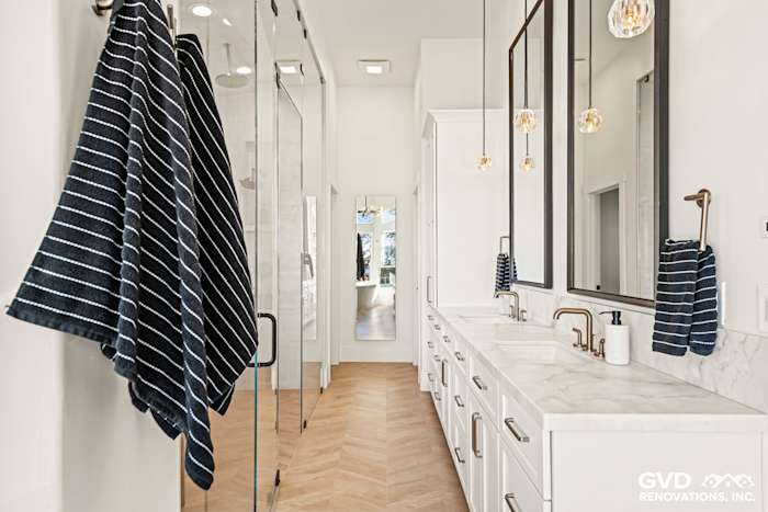 Luxurious El Dorado Hills bathroom featuring white cabinetry, marble countertops, glass shower, and stylish lighting