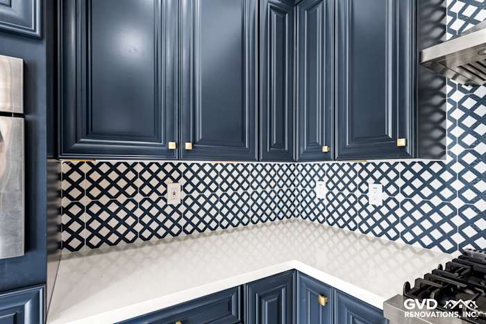 Navy blue kitchen cabinets with intricate backsplash pattern and white quartz countertop in Sacramento remodel