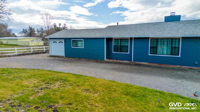 Sonoma home featuring new James Hardie Evening Blue siding and Arctic White trim, with a gravel driveway and green lawn