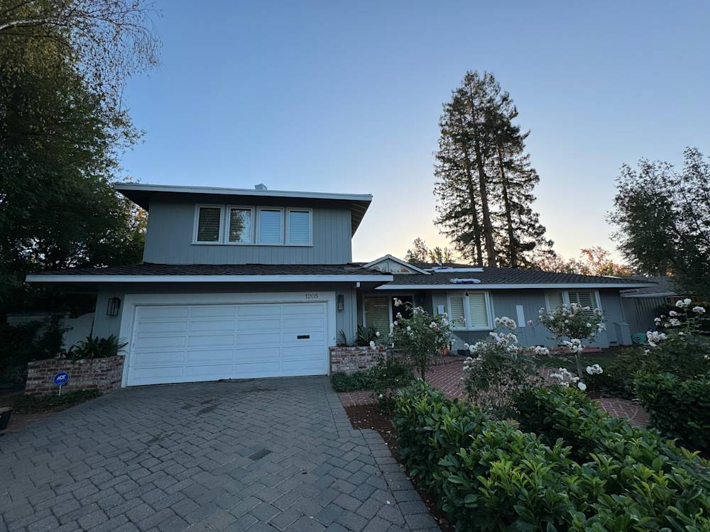 Two-story home in Sacramento with grey siding and a brick driveway, surrounded by landscaping