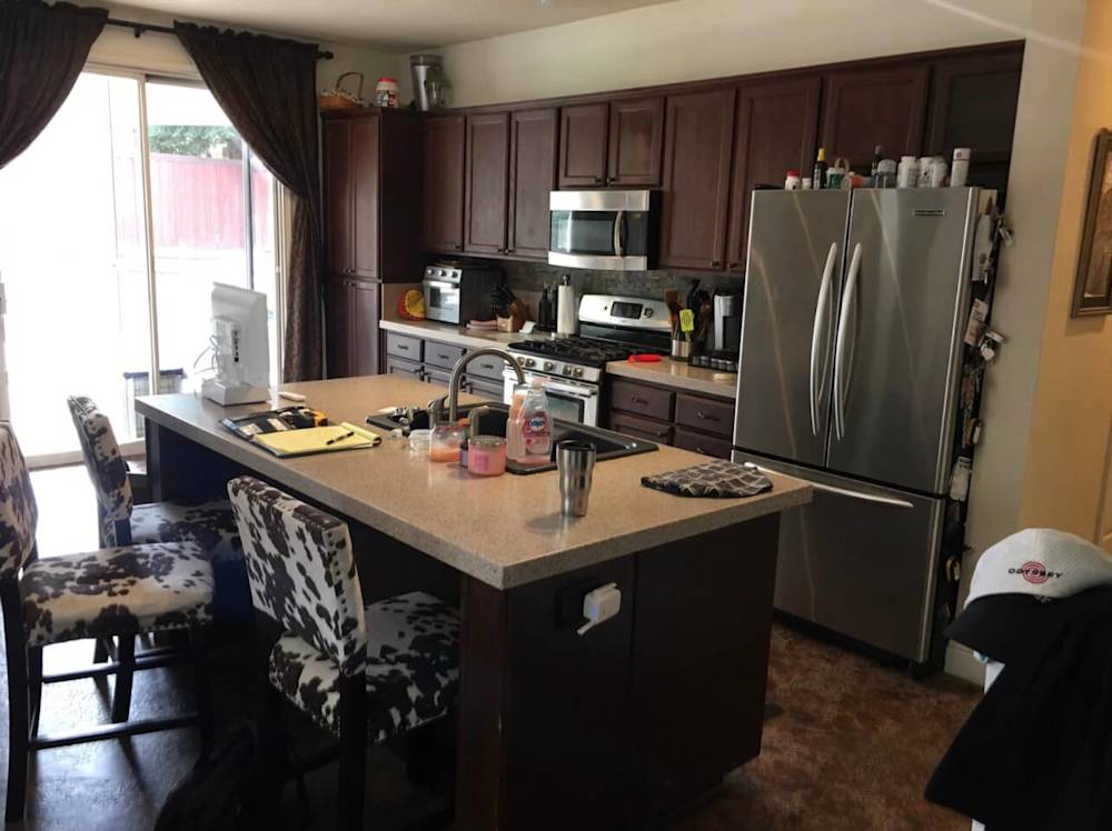 Dark wood cabinets, outdated countertop, and cluttered kitchen space