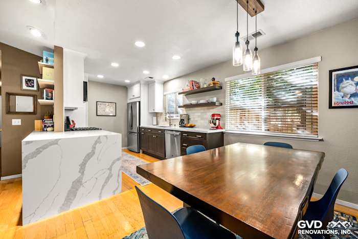 Modern kitchen remodel in Davis, featuring a white quartz island, dark cabinets, and a wooden dining table