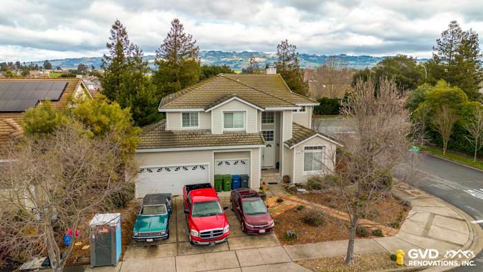 Two-story home in Petaluma, CA with James Hardie Cobble Stone siding, Arctic White trim, and driveway of parked cars
