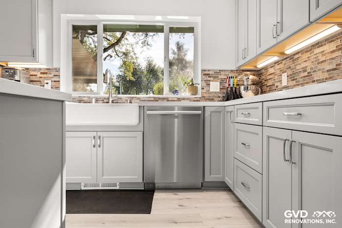Modern kitchen with gray cabinetry, a farmhouse sink, stainless steel dishwasher, and mosaic backsplash in Greenwood, CA