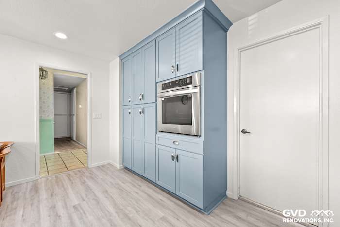 Modern kitchen remodel in Elk Grove, featuring blue Waypoint cabinets, built-in oven, and light laminate flooring