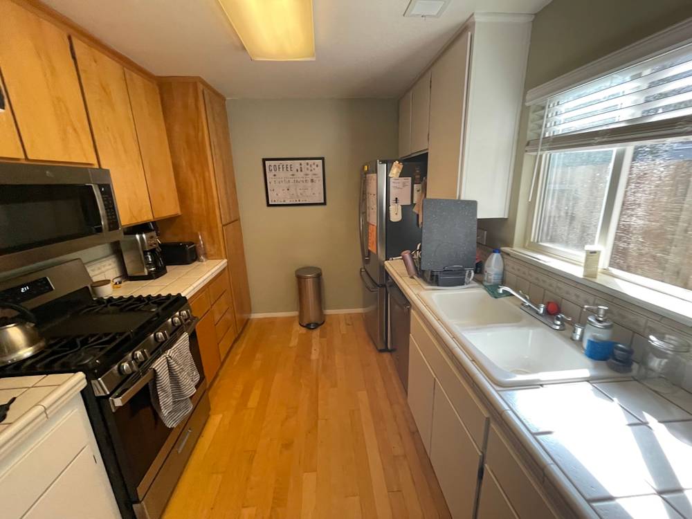 Narrow kitchen with wood cabinetry, stainless steel appliances, and light-colored countertops in Sacramento