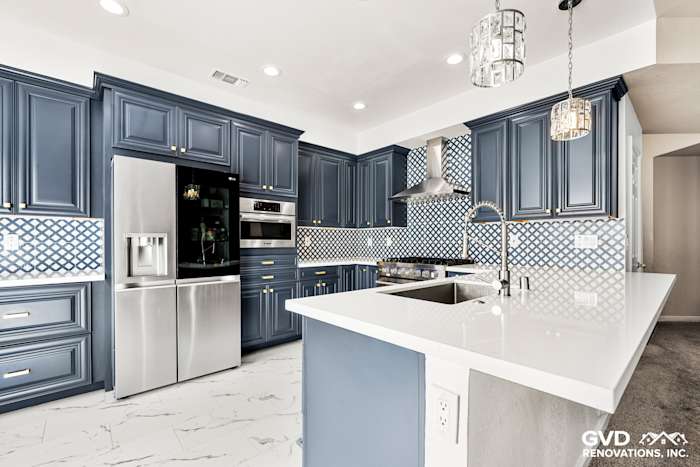 Modern kitchen with navy blue cabinets, white quartz countertops, and decorative backsplash in Sacramento
