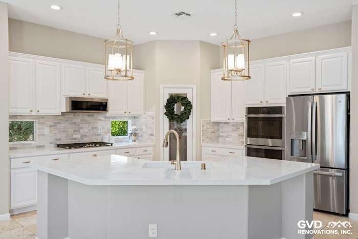 Modern kitchen renovation featuring white cabinetry, quartz countertops, double ovens, and elegant pendant lighting
