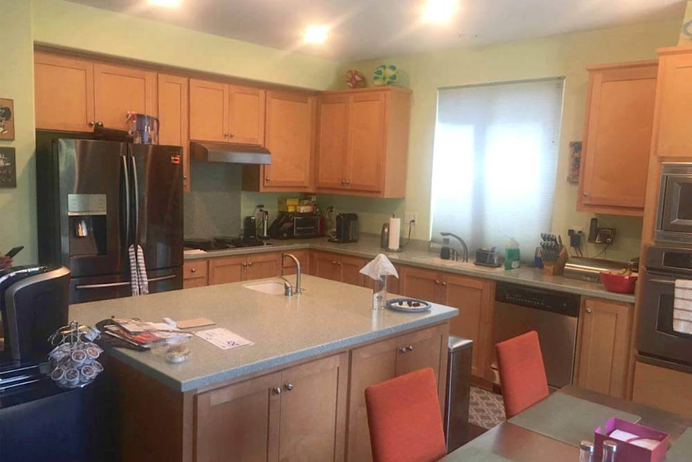 Outdated kitchen with maple cabinets, gray countertops, and orange chairs