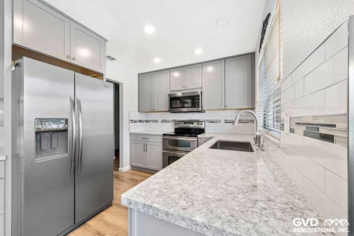 Modern kitchen remodel in Carmichael featuring gray cabinets, stainless steel appliances, and a granite countertop