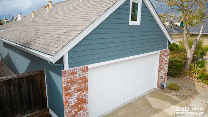 Home exterior featuring Evening Blue James Hardie siding and Arctic White trim, with a brick accent around the garage